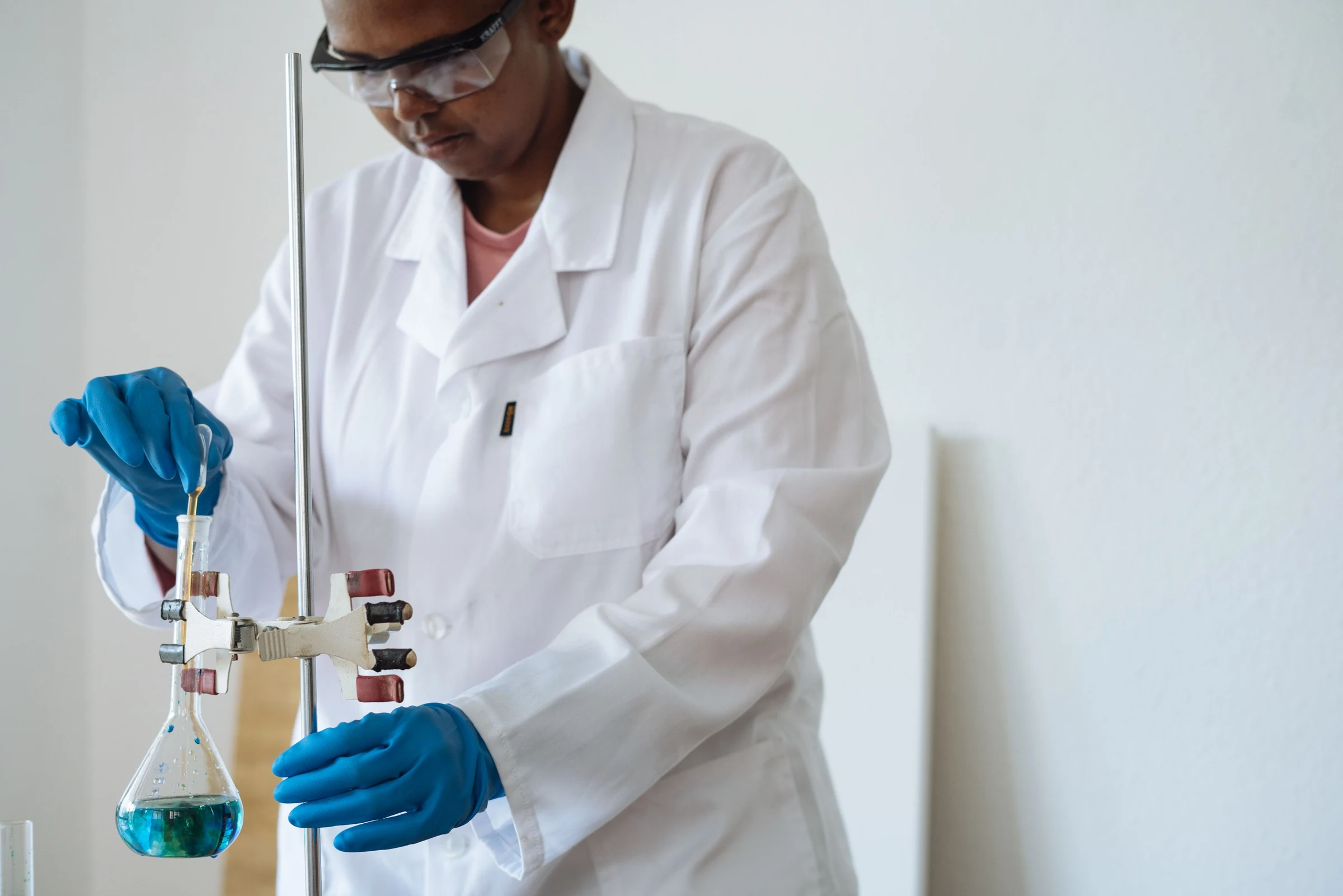 Researcher transferring liquid into an Erlenmeyer flask in a laboratory